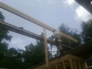 Carpenter setting a ridge beam over a new addition frame — Ice Dam Removal by Roofing Brothers in Clinton Corners