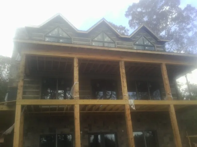 Dormers and porch framing on a large log home under construction — Roof Coating work by our crew in Clinton Corners