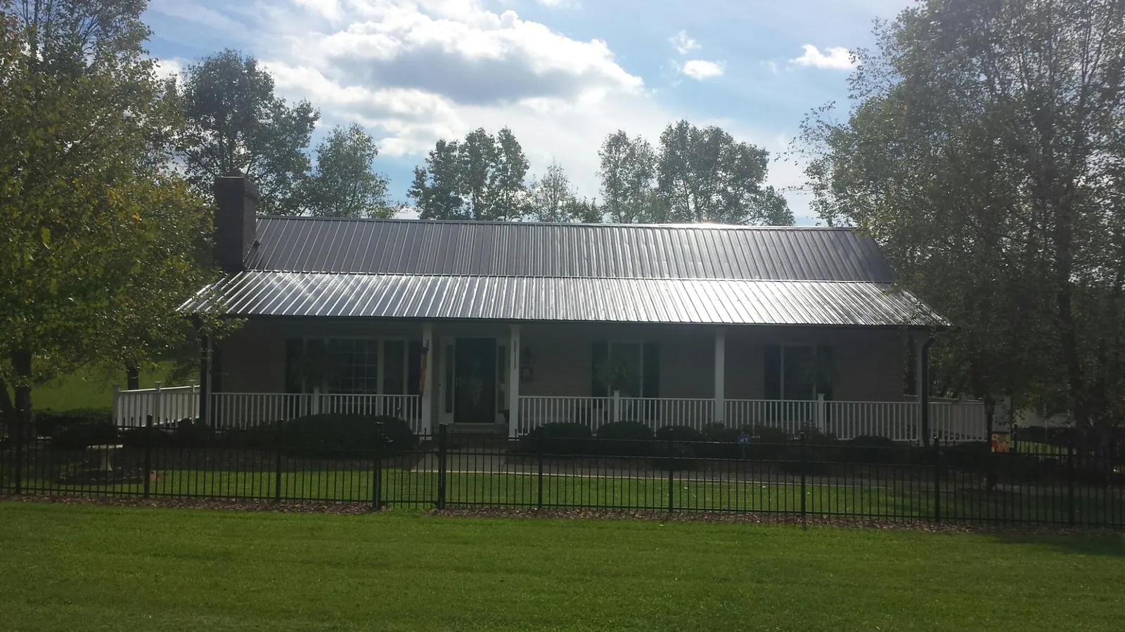 Gray metal roof on a brick ranch with a full width front porch — Gutter Guard Installation work by our crew in Clinton Corners