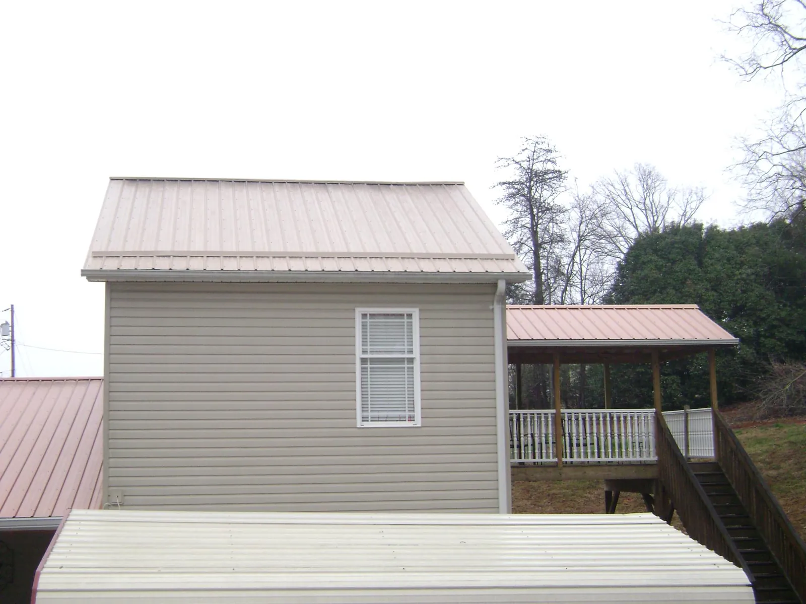 Tan metal roofs on a two story addition and attached porch, from a Roof Replacement job in Clinton Corners