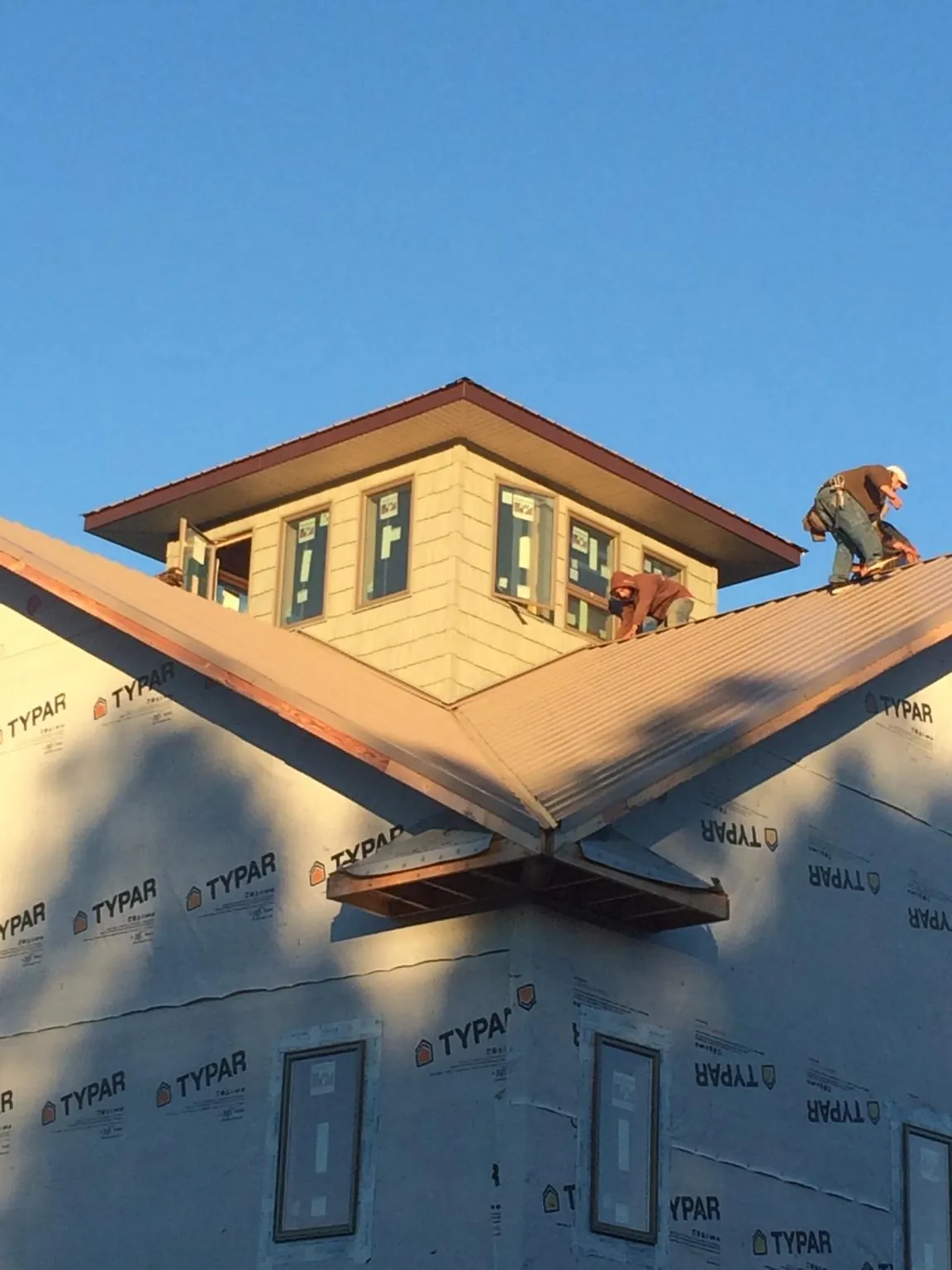 Roofers working around a rooftop cupola on a new metal roof at sunset — Roof Waterproofing in Clinton Corners by Roofing Brothers